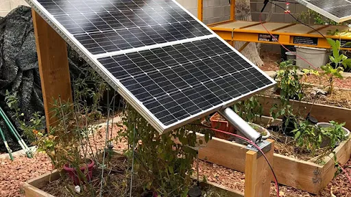 Solar panel of the backyard power plant over raised garden beds, from No Grid Survival Projects